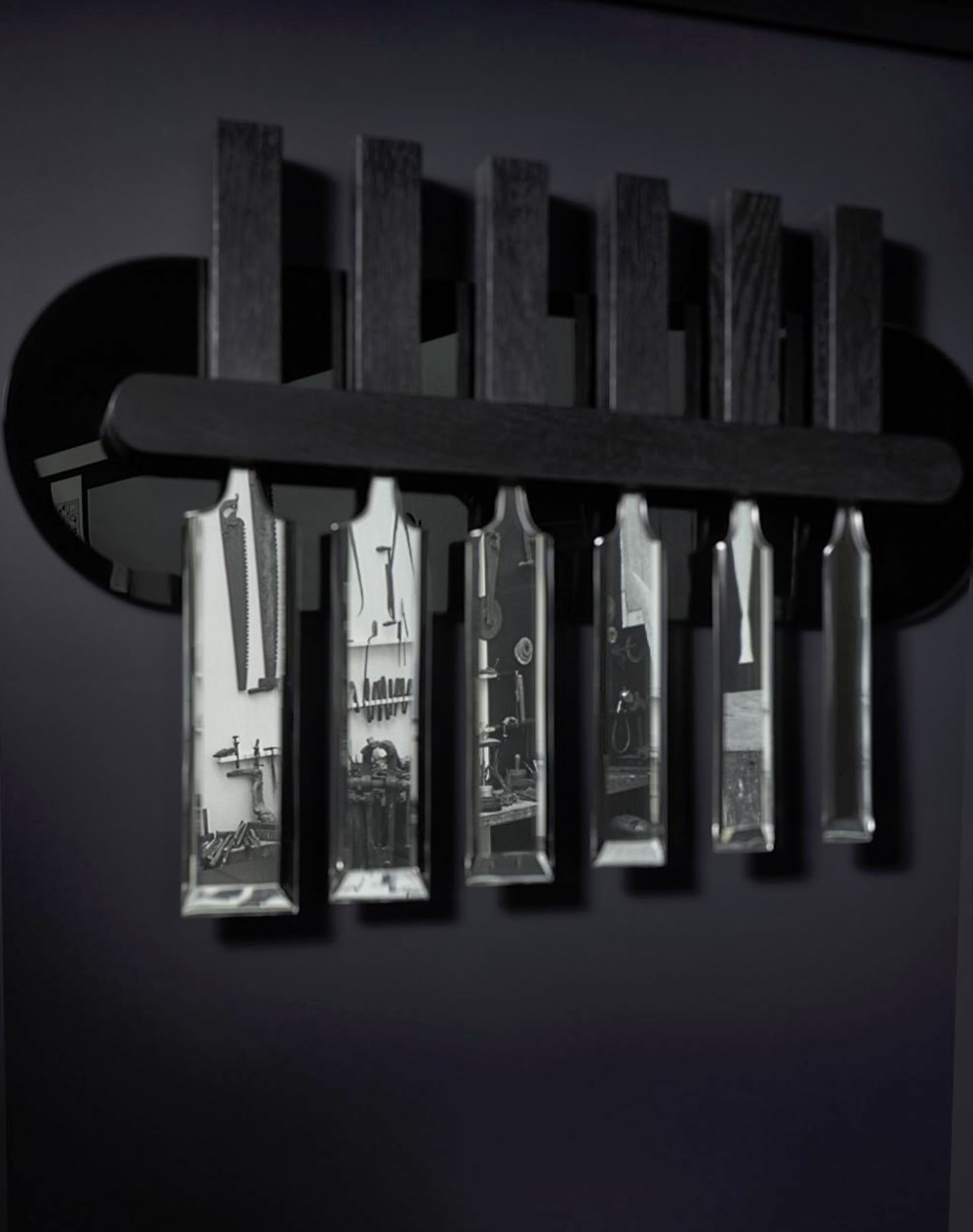 Six lames de ciseaux à bois en miroir suspendues à un support de chêne noir ; chacune reflète un fragment de l’atelier de Brancusi