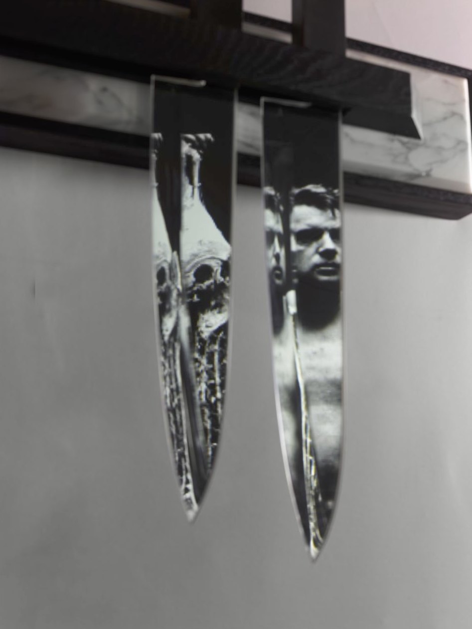 Deux couteaux en miroir sur fond de marbre ; dans leurs lames, le portrait de Francis Bacon tenant des carcasses
