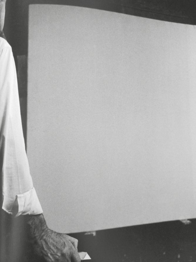 Une main présente une toile blanche vierge, photographie noir et blanc