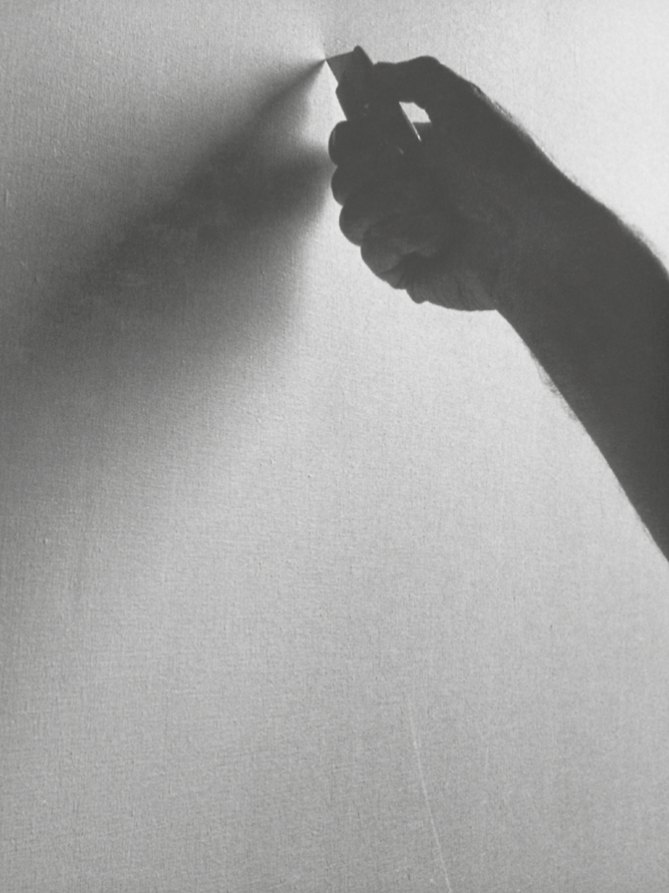 Ombre d’une main tenant une lame contre la toile, au moment de l’incision