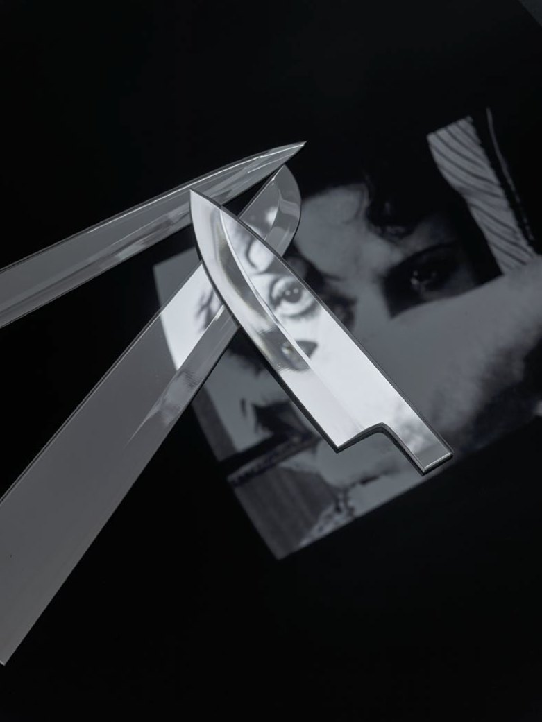 Lames de couteau en miroir croisées sur le visage et l’œil du photogramme